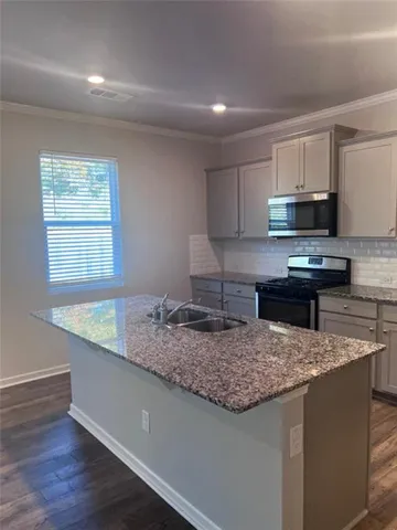 a kitchen with kitchen island granite countertop a sink a counter top space and appliances