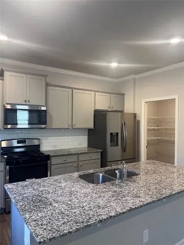 a kitchen with kitchen island granite countertop a sink stove and refrigerator