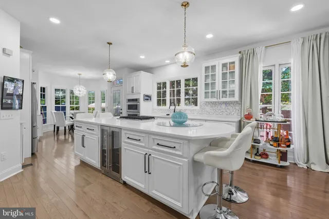 a kitchen with stainless steel appliances granite countertop a stove top oven a sink dishwasher a dining table and chairs with wooden floor