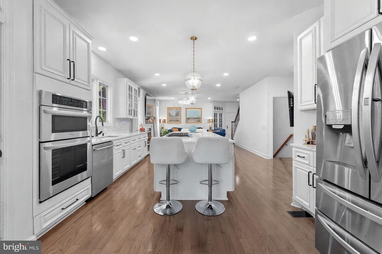 2725 Robaleed Way Herndon, VA 20171 - Photo 15 of 45 a kitchen with stainless steel appliances kitchen island granite countertop a refrigerator a stove oven and white cabinets with wooden floor