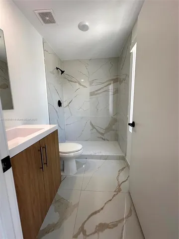 a white toilet sitting next to a bathroom sink and a shower
