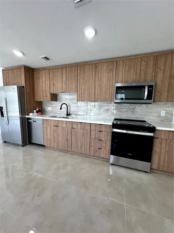 a kitchen with stainless steel appliances a stove a sink and a microwave