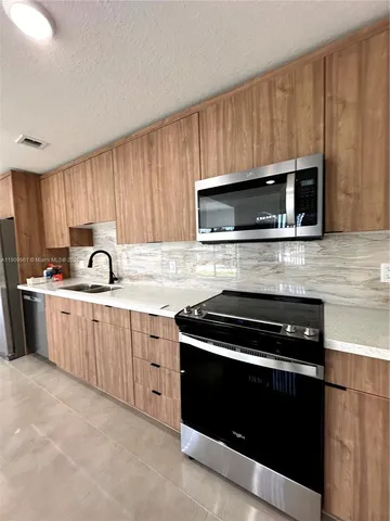 a kitchen with granite countertop a stove a microwave a sink and cabinets
