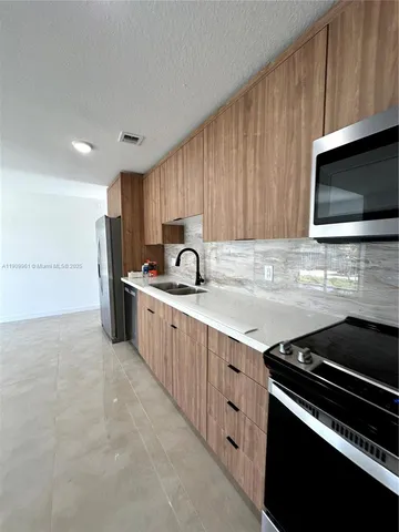 a kitchen with stainless steel appliances a stove a sink and a microwave