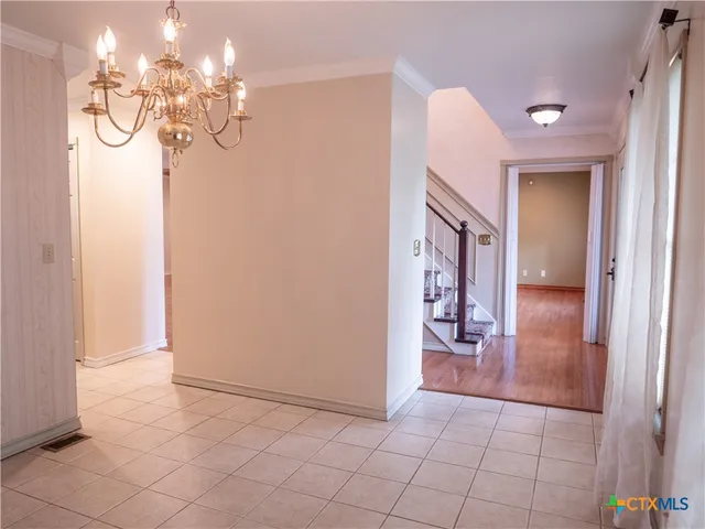a view of a hallway with chandelier and dining area