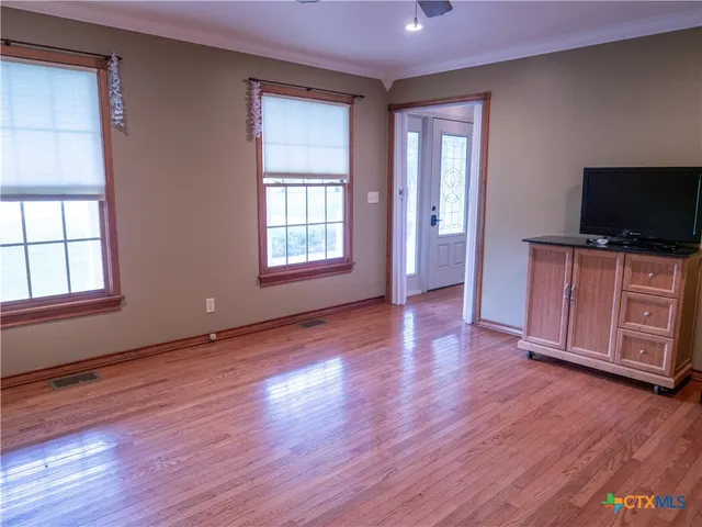 an empty room with wooden floor and windows