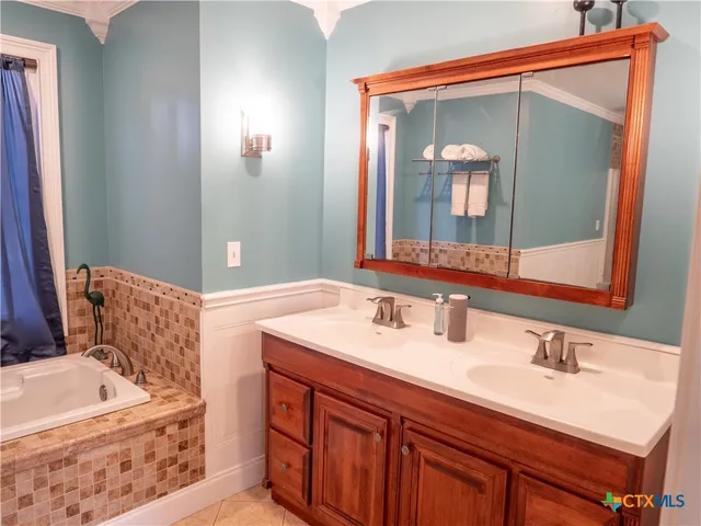 a bathroom with a tub a sink and mirror
