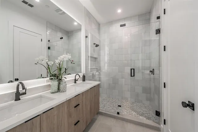 a bathroom with a double vanity sink mirror and shower
