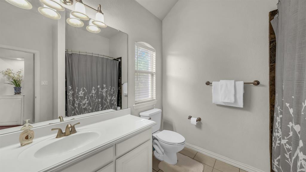203 Mockingbird Lane Aledo, TX 76008 - Photo 31 of 37 Bathroom featuring a single vanity with an integrated sink, broad wall mirror, and brushed bronze fixtures