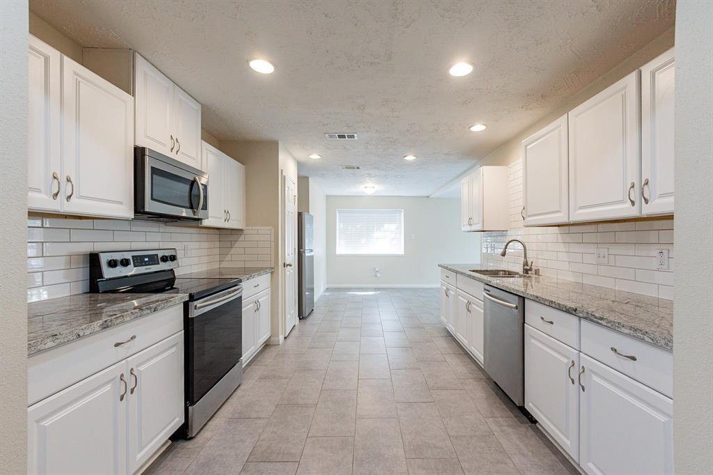 a large kitchen with stainless steel appliances granite countertop a stove top oven a sink dishwasher and a microwave oven on the blue kitchen countertops
