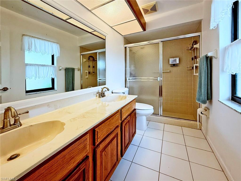 2005 Pine Isle Lane, Unit 2005 Naples, FL 34112 - Photo 9 of 23 Owner's Bathroom with double vanity, a stall shower, light tile flooring and window for extra ventilation.