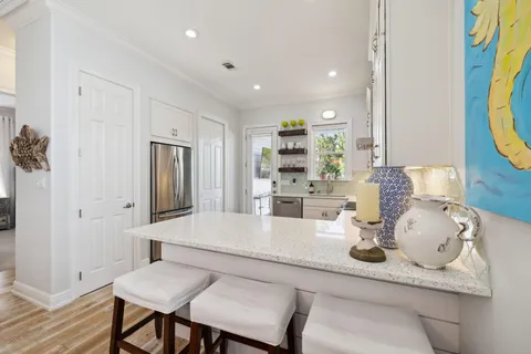 a large white kitchen with a refrigerator a sink dishwasher a oven and white cabinets with wooden floor