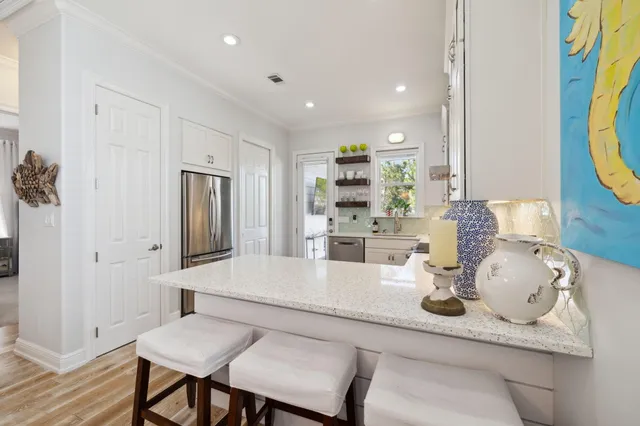 a large white kitchen with a refrigerator a sink dishwasher a oven and white cabinets with wooden floor