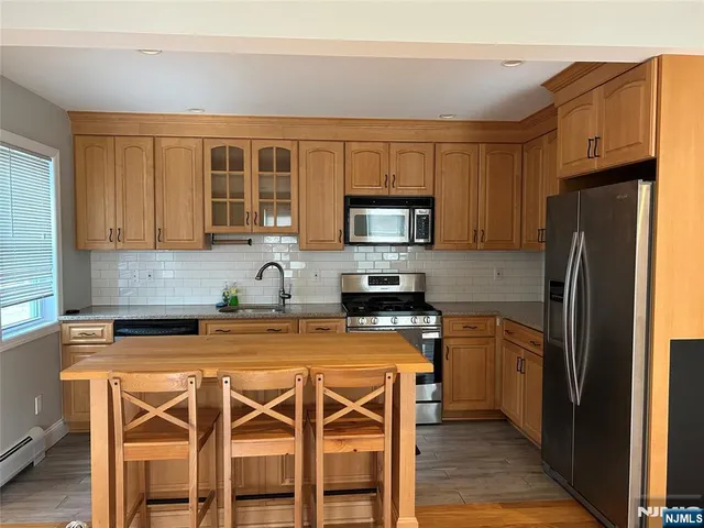 a kitchen with stainless steel appliances a stove a sink refrigerator and a microwave