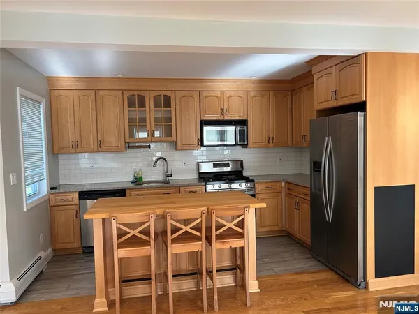 a kitchen with stainless steel appliances granite countertop a stove a refrigerator a sink a dining table and chairs