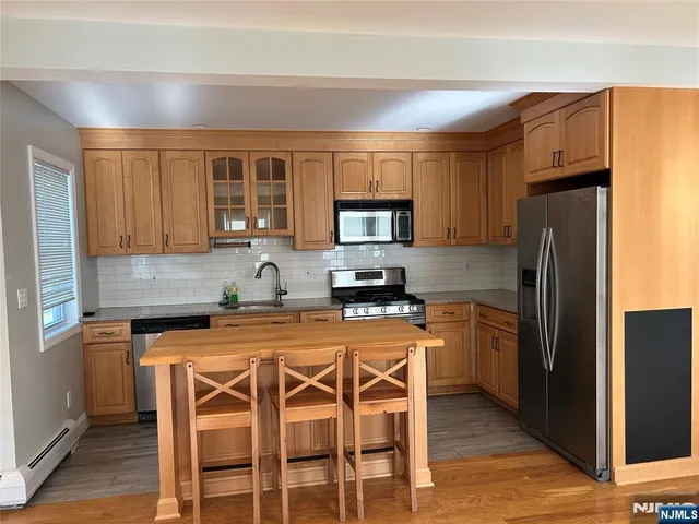 a kitchen with stainless steel appliances granite countertop a stove a refrigerator a sink a dining table and chairs