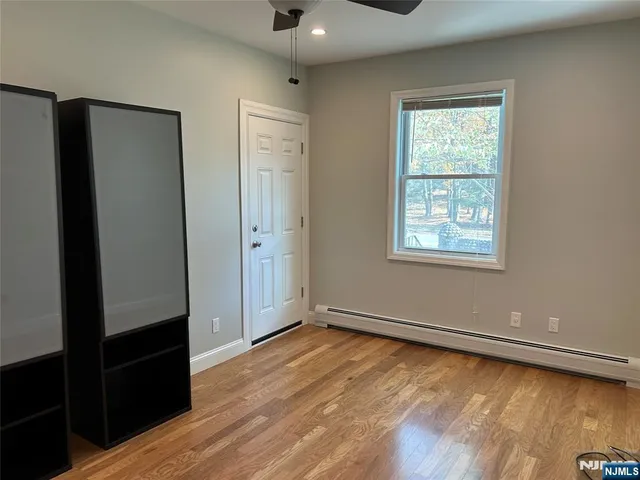 an empty room with wooden floor closet and windows