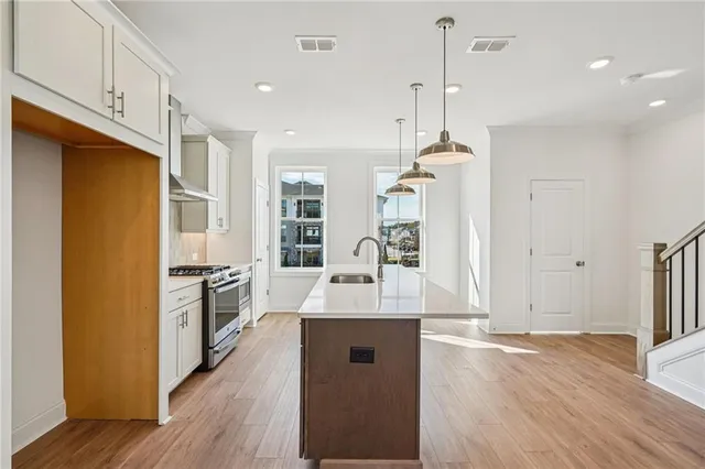 a kitchen with stainless steel appliances granite countertop a refrigerator a sink dishwasher a stove with wooden floor