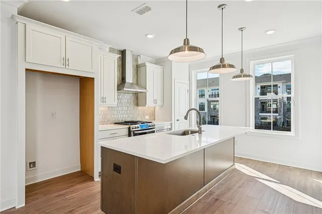 a kitchen with stainless steel appliances granite countertop a sink a stove and a wooden floor