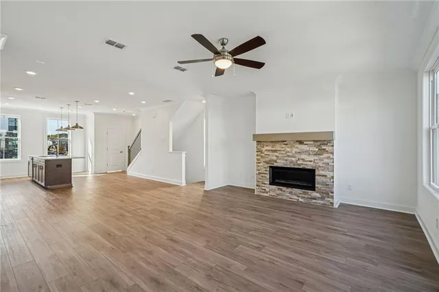 a view of a livingroom with a fireplace a ceiling fan and a kitchen view