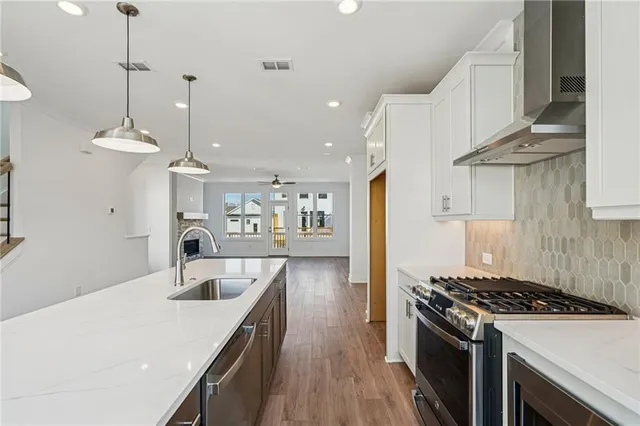 a kitchen with stainless steel appliances granite countertop a sink a stove and a wooden floors