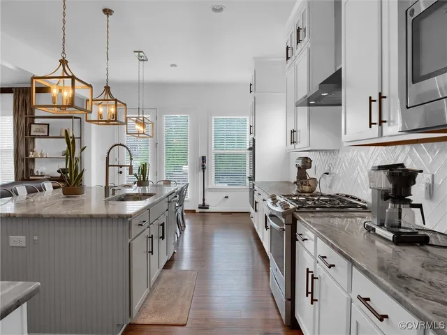 a kitchen with stainless steel appliances granite countertop a sink a stove and a wooden floors