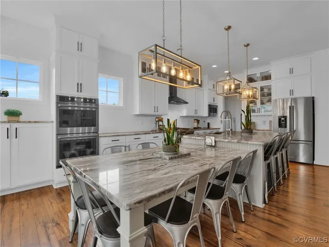 a kitchen with stainless steel appliances granite countertop a table chairs stove and refrigerator