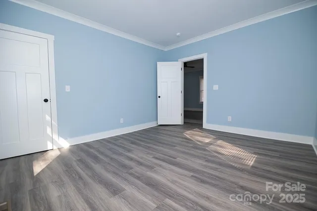 a view of an empty room with wooden floor and closet
