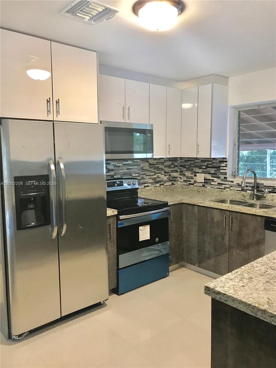 3700 Taft Street Hollywood, FL 33021 - Photo 4 of 10 a kitchen with stainless steel appliances kitchen island granite countertop a stove a sink and a microwave