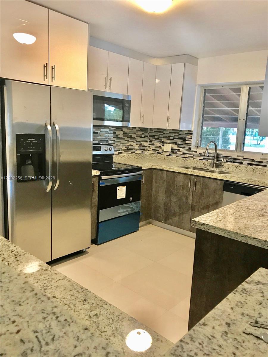 3700 Taft Street Hollywood, FL 33021 - Photo 8 of 10 a kitchen with stainless steel appliances granite countertop a sink a stove and a refrigerator