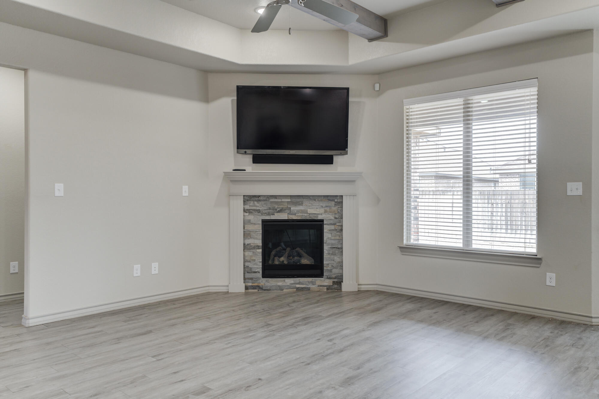 7614 62nd Street Lubbock, TX 79407 - Photo 20 of 54 a living room with a fireplace a flat screen tv and a window