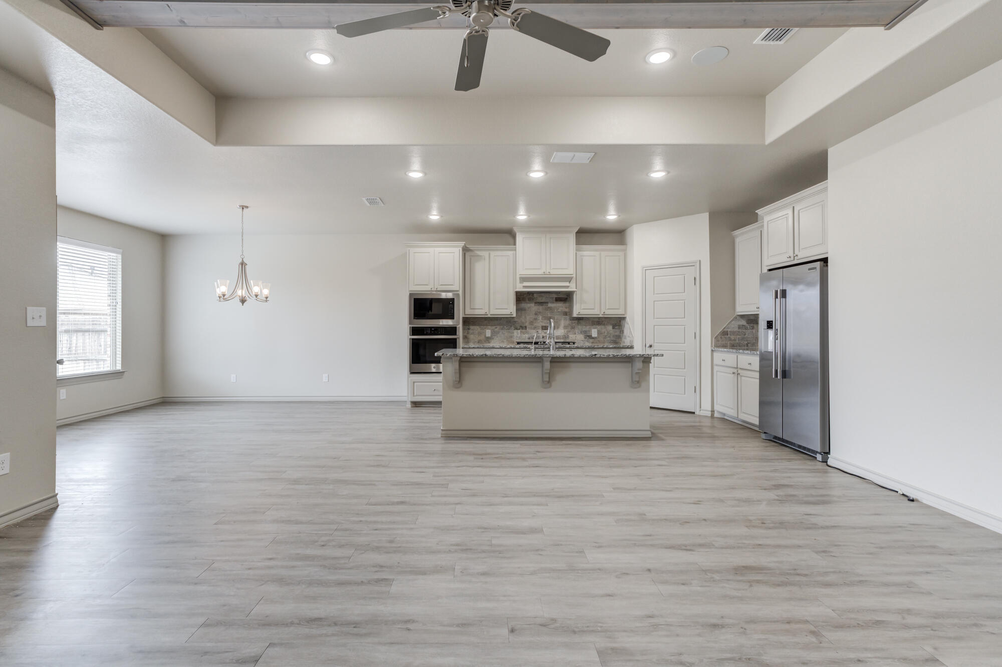 7614 62nd Street Lubbock, TX 79407 - Photo 23 of 54 a large kitchen with kitchen island a stove a refrigerator cabinets and wooden floor