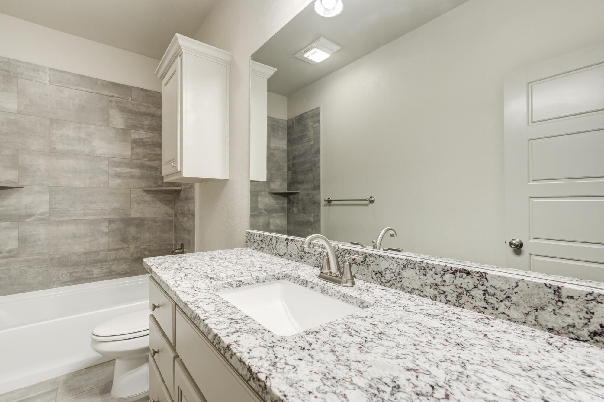 7614 62nd Street Lubbock, TX 79407 - Photo 43 of 54 a bathroom with a granite countertop sink a toilet and bathtub