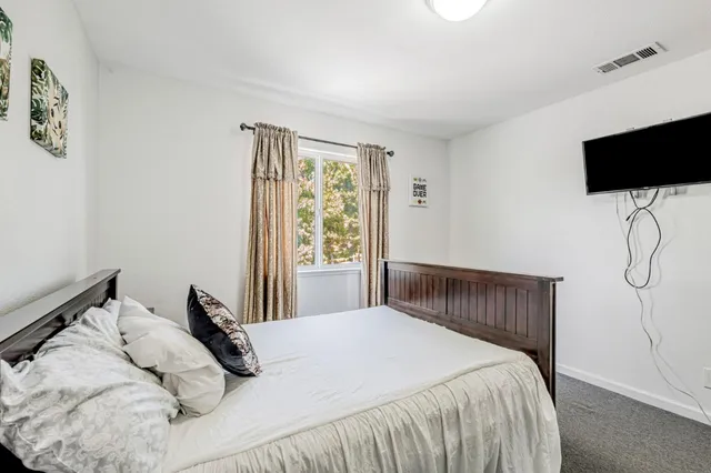 a bedroom with a bed tv and a window