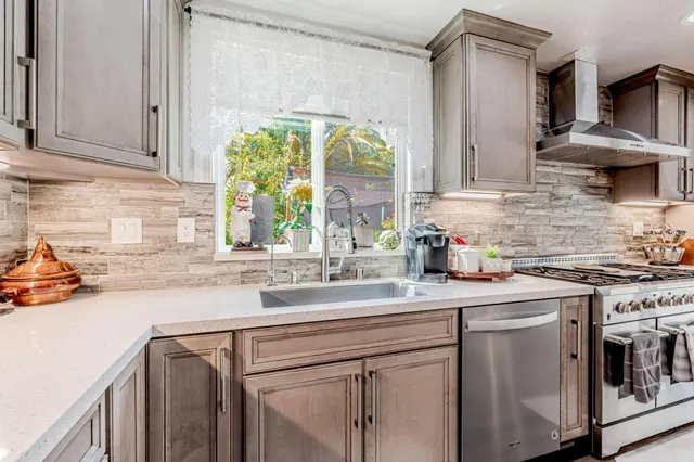 a kitchen with stainless steel appliances granite countertop a sink a stove and a white wooden cabinets
