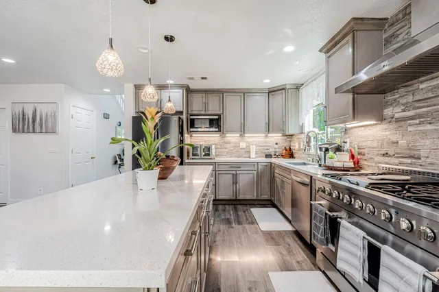 a kitchen with stainless steel appliances granite countertop a sink a stove and a refrigerator
