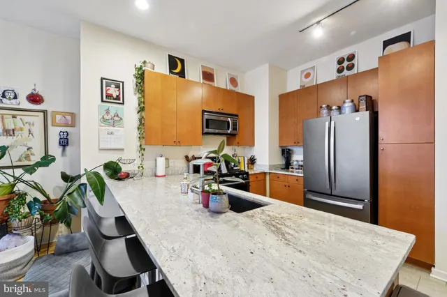 a kitchen with granite countertop a refrigerator a stove a sink a dining table and chairs with wooden floor