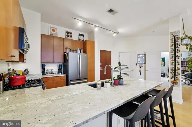 a kitchen with stainless steel appliances kitchen island granite countertop a table chairs in it and wooden floors