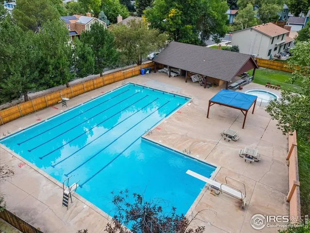 a view of swimming pool with seating space and trees in the background