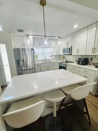 a kitchen with kitchen island a white cabinets and chairs