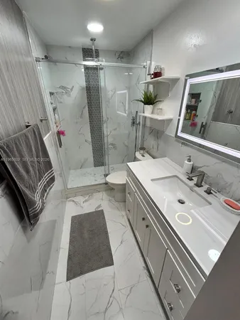 a bathroom with a sink a toilet a mirror and shower