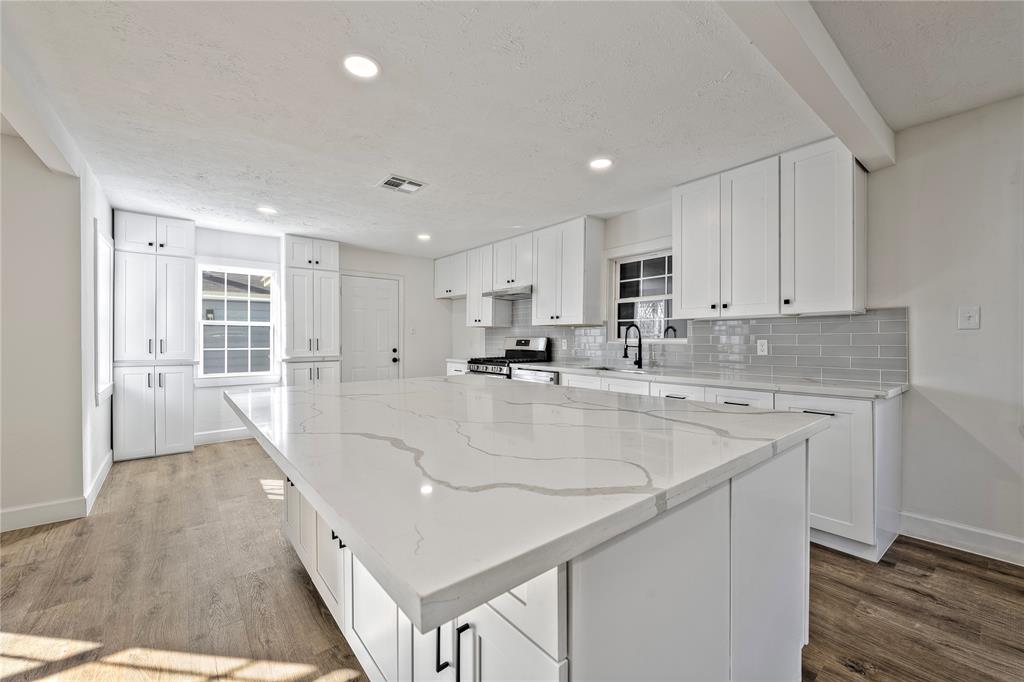 a large white kitchen with wooden floor