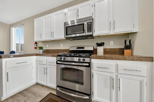 a kitchen with granite countertop white cabinets stainless steel appliances and sink