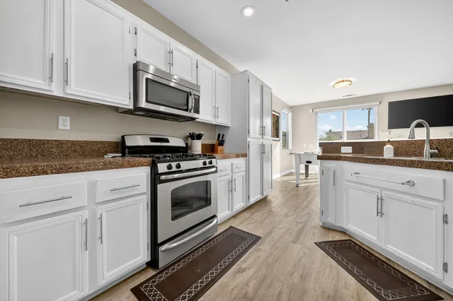 a kitchen with stainless steel appliances granite countertop a stove a sink and a microwave