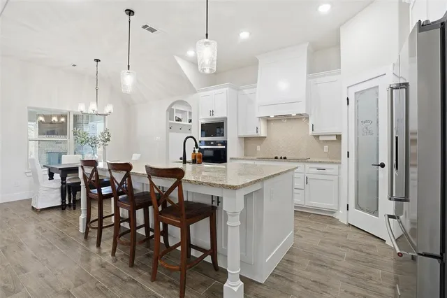 a large kitchen with cabinets chairs and stainless steel appliances