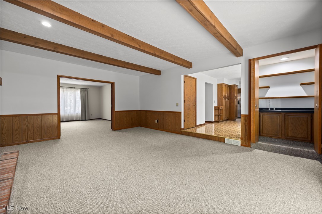 1711 Gulf Road Elyria, OH 44035 - Photo 7 of 50 Unfurnished living room featuring light carpet, beam ceiling, recessed lighting, and a wainscoted wall