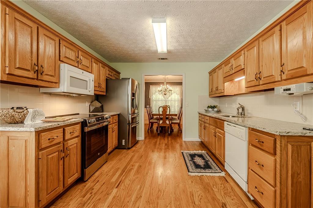 160 Vinny's Way Covington, GA 30014 - Photo 7 of 51 a kitchen with granite countertop wooden floors wooden cabinets a sink and appliances