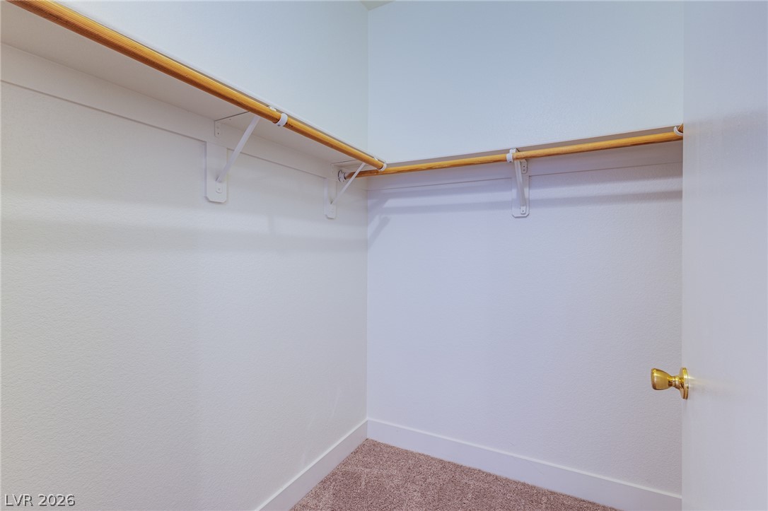 9050 West Warm Springs Road, Unit 1011 Las Vegas, NV 89148 - Photo 17 of 32 A well-organized closet offers ample storage space, featuring a sturdy hanging rod and soft carpeting.