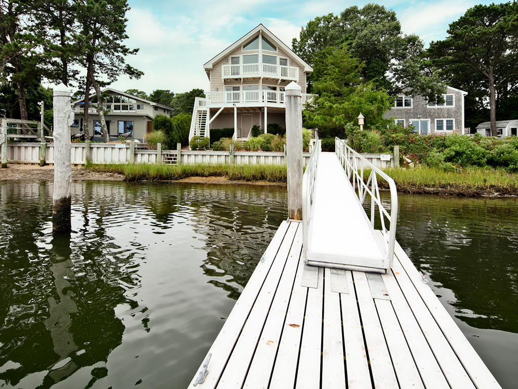 6 Great River Road Mashpee, MA 02649 - Photo 1 of 21 a view of a brick house next to a lake with a large trees