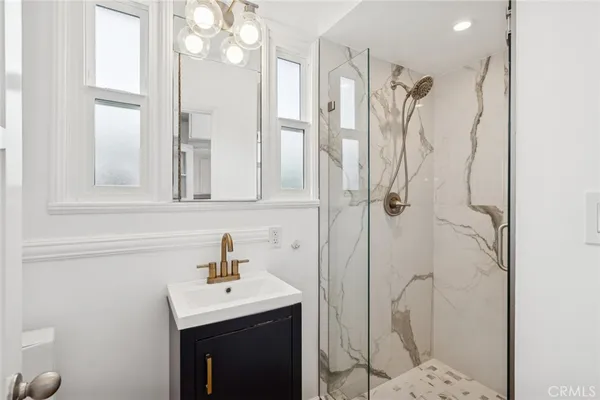 a bathroom with a sink a mirror a vanity and shower